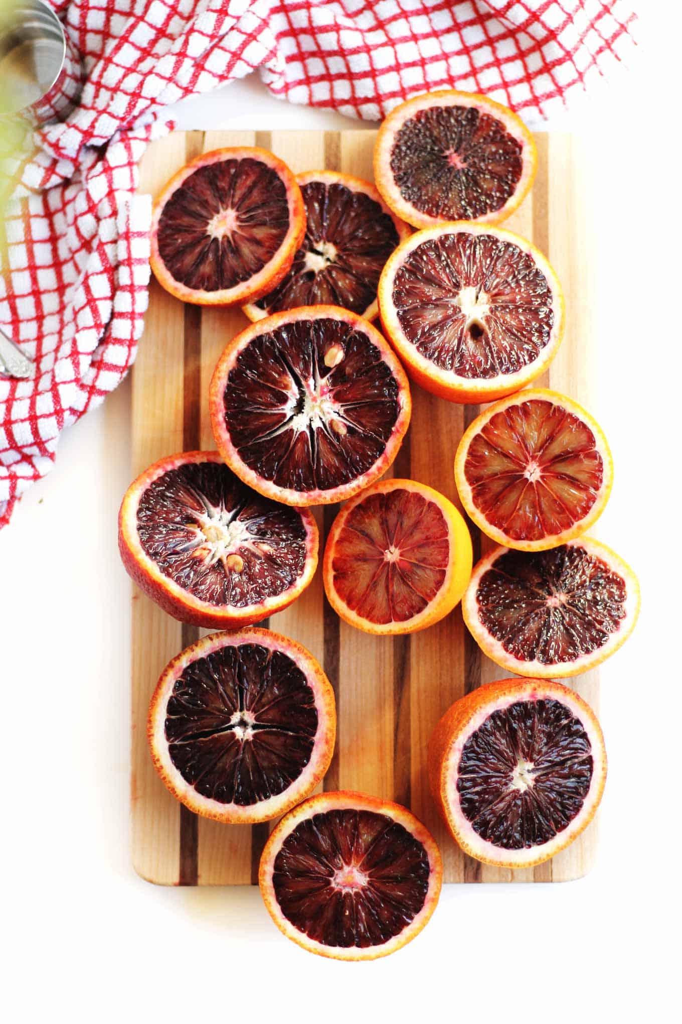A photo of blood oranges cut in half and on a wooden cutting board