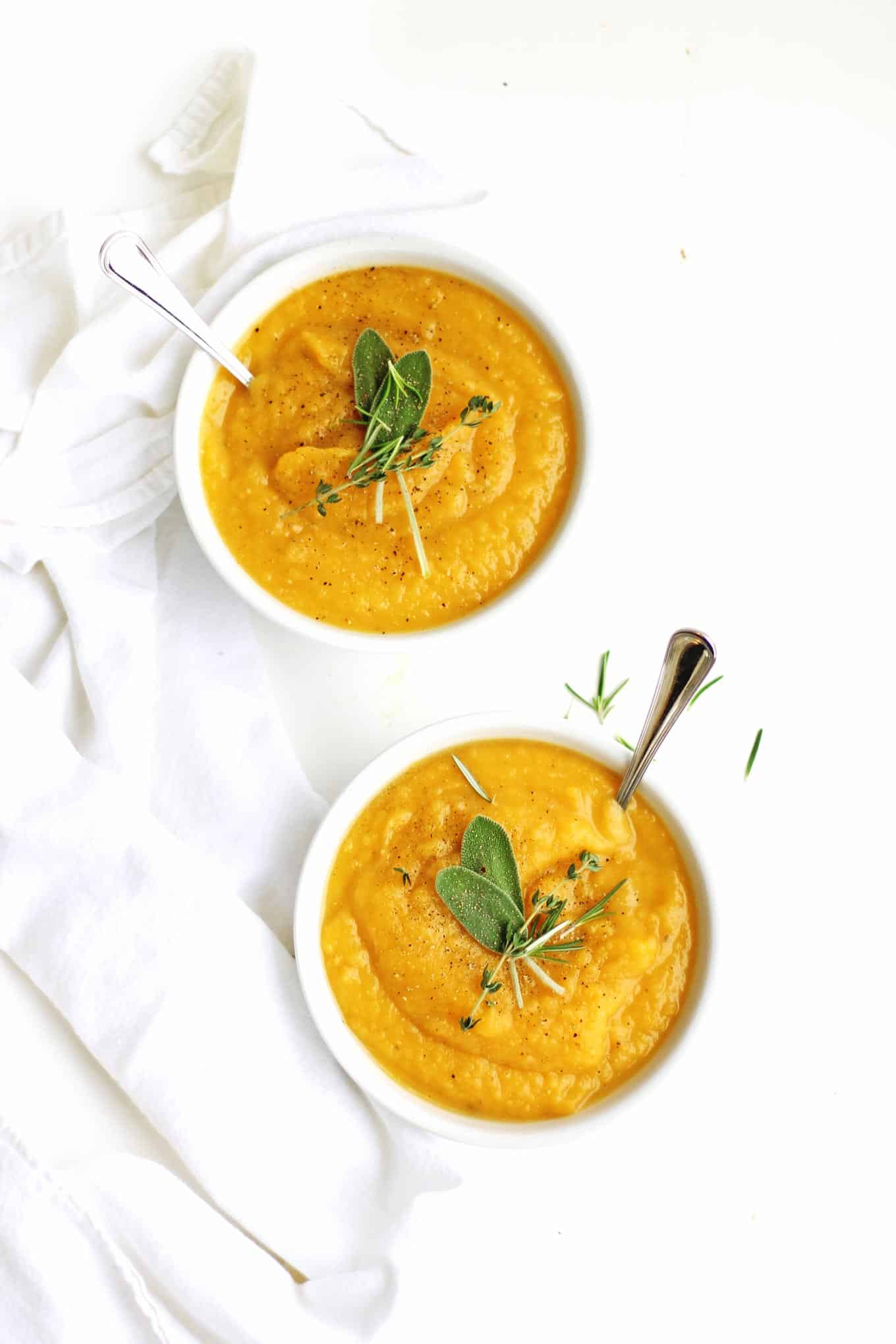 Bowls of butternut squash leek soup with herbs and spoons