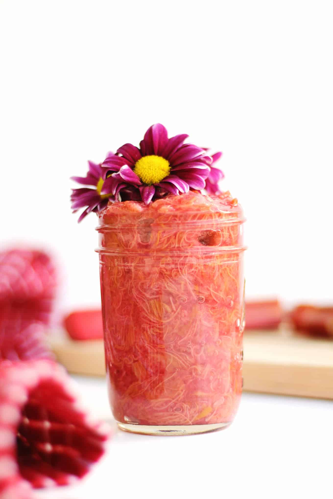 Rhubarb jam in a mason jar topped with purple flowers