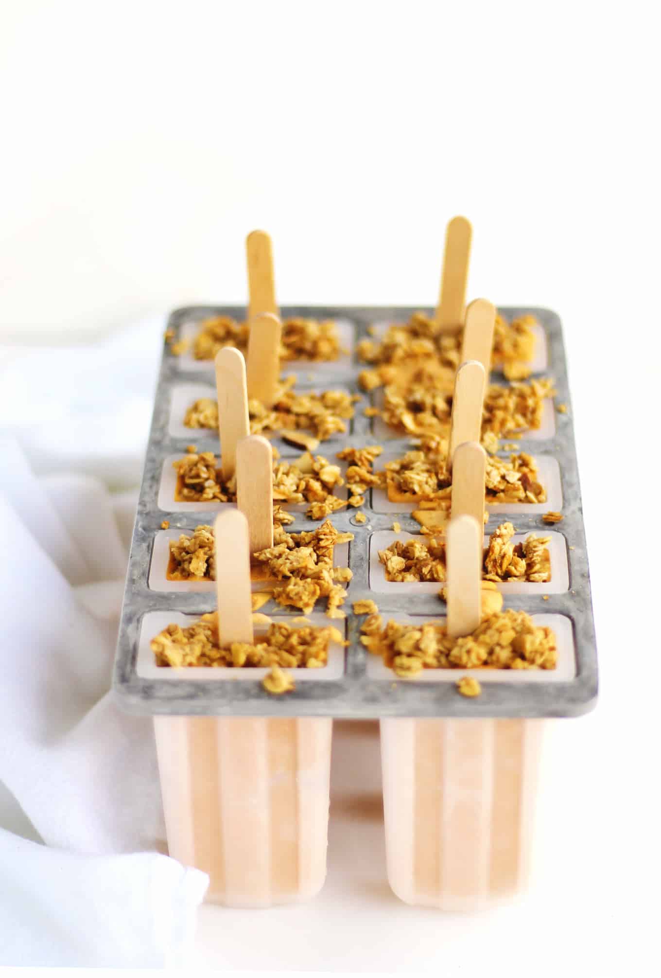 Pumpkin breakfast popsicles in a popsicle mold with granola on top