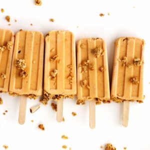 Pumpkin popsicles in a line with granola scattered