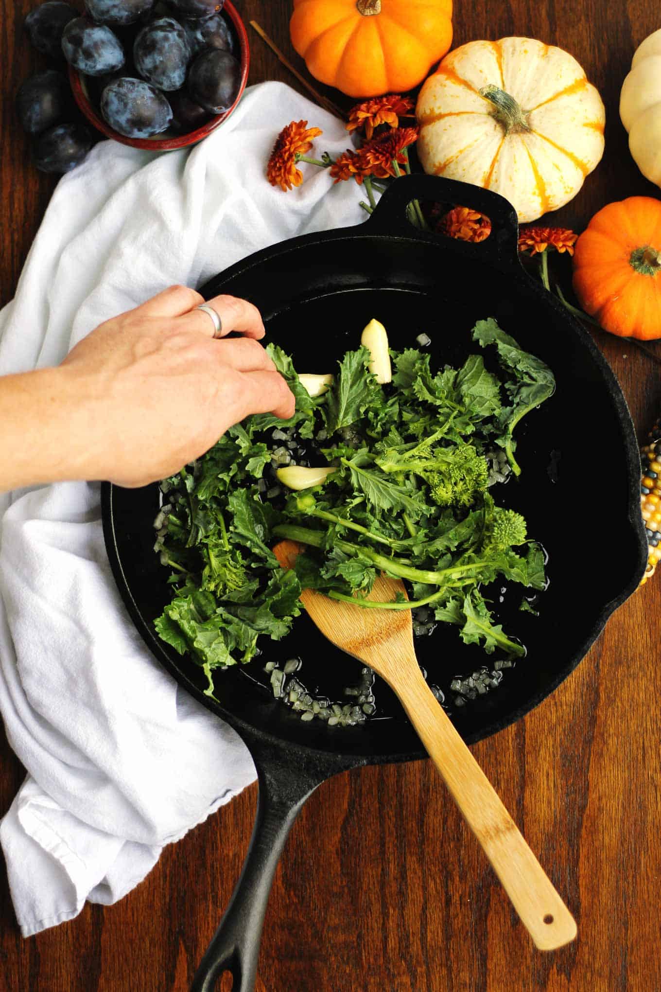 cooking broccoli rabe in a black skillet with garlic