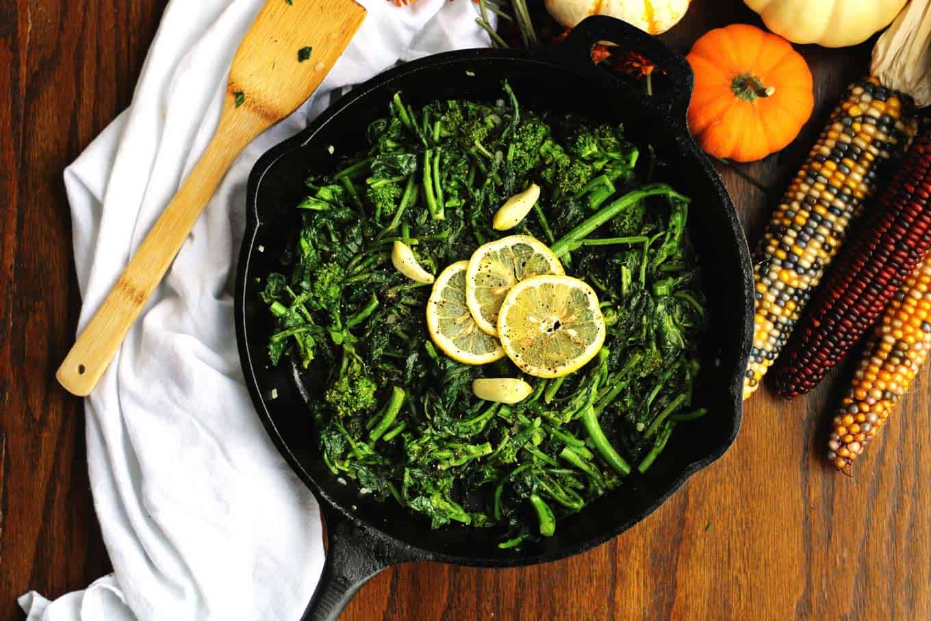 sauteed broccoli rabe in a cast iron skillet with with lemon slices