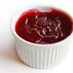 A photo of jellied cranberry sauce in a white ramekin.