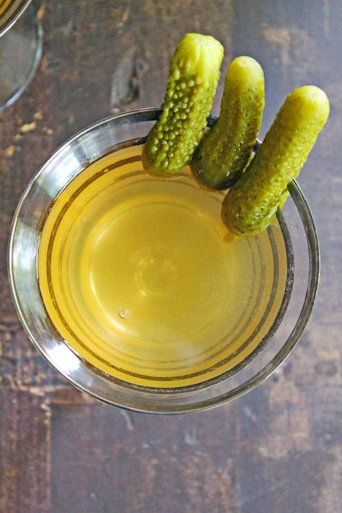 An overhead photo of a pickle juice cocktail with pickles for garnish.