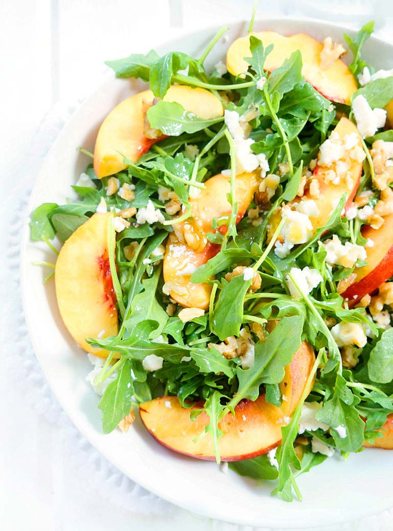 nectarine salad with arugula in a white bowl