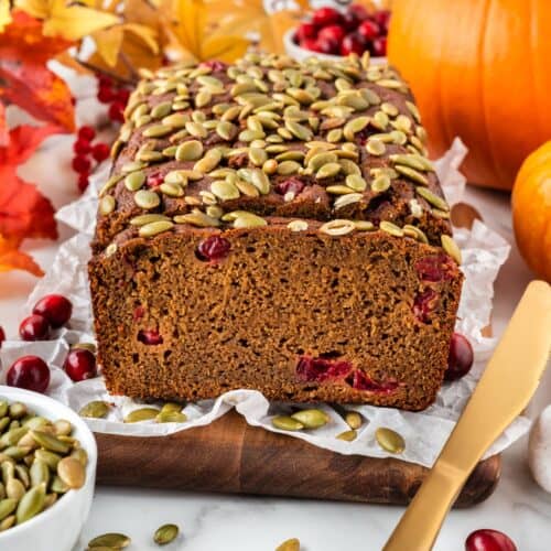A square photo of a loaf of pumpkin cranberry bread.