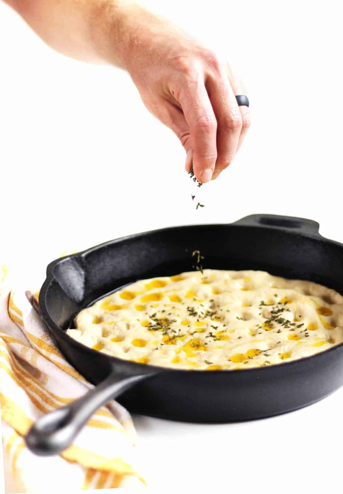 sprinkling rosemary on focaccia dough