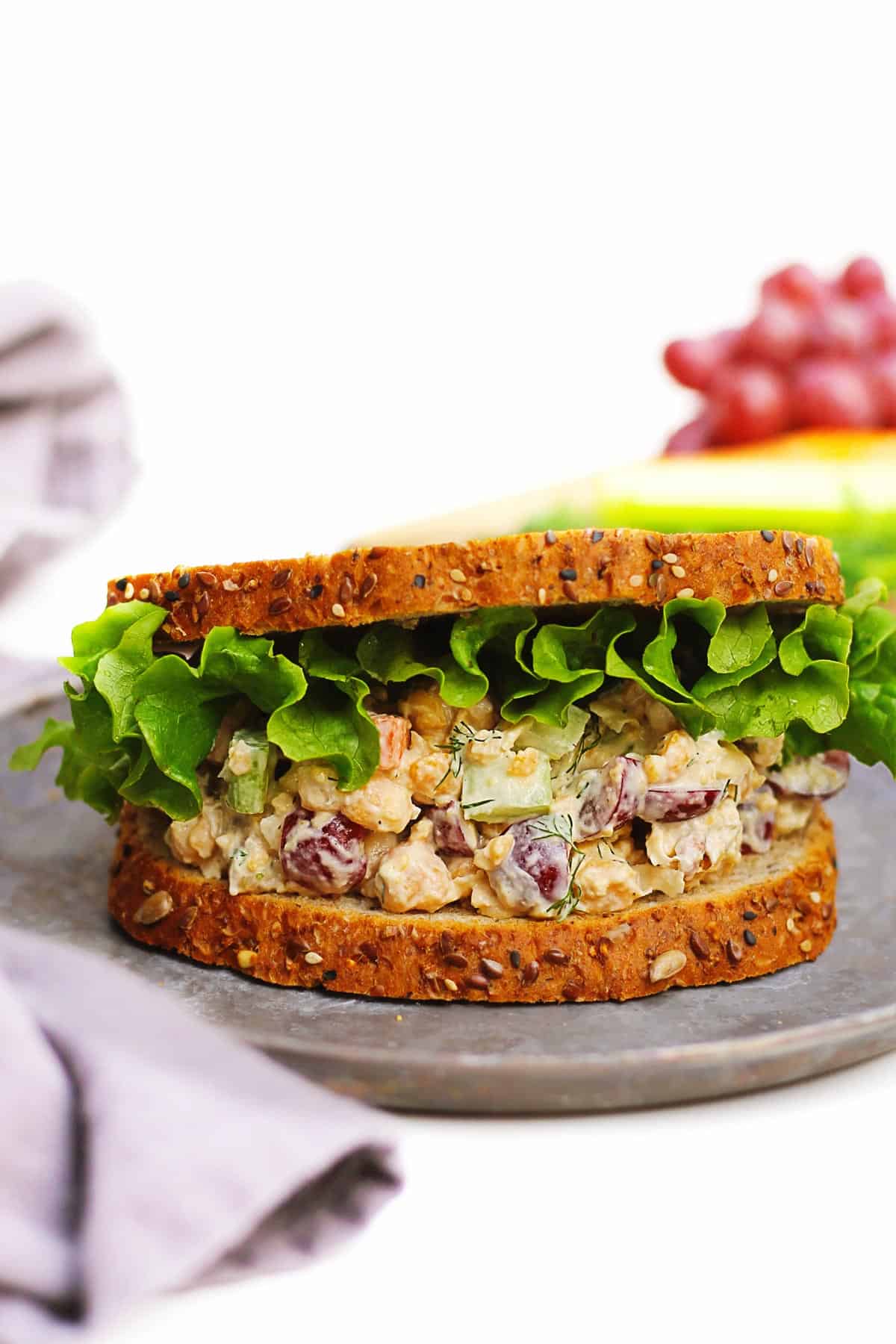 A photo of a chickpea salad sandwich with green lettuce on wheat bread.