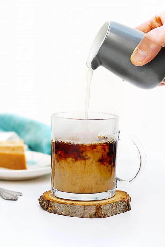 pouring milk into a cup of coffee
