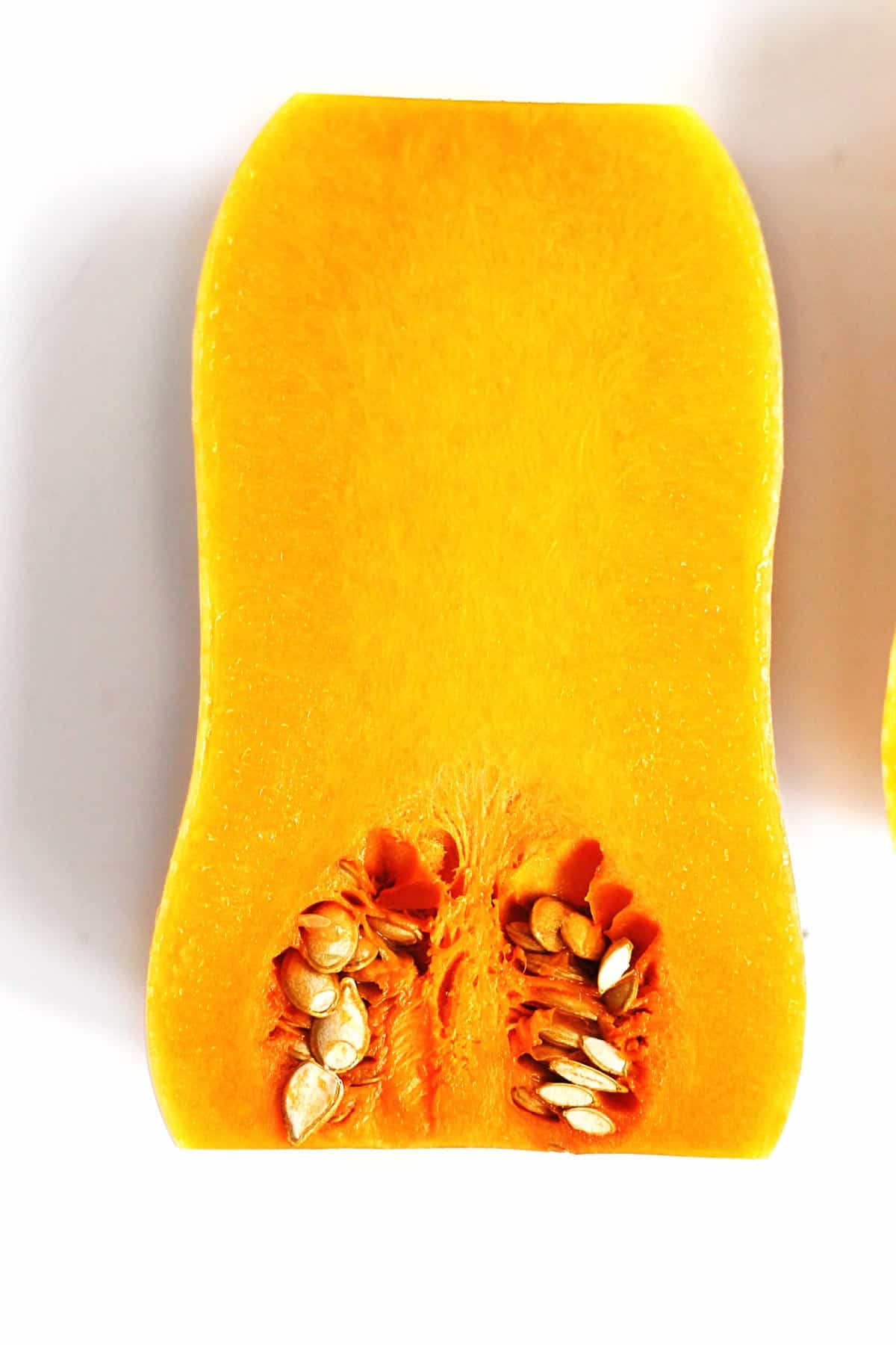 A photo of the inside of half of a butternut squash with flesh and seeds.