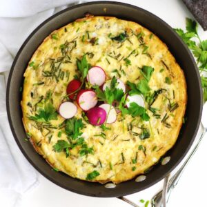 Spinach artichoke cottage cheese frittata in a pan with radishes on top