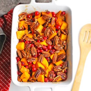 Butternut squash with cranberries and pecans in a white dish