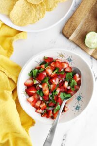 Fresh strawberry salsa in a white bowl with a silver spoon