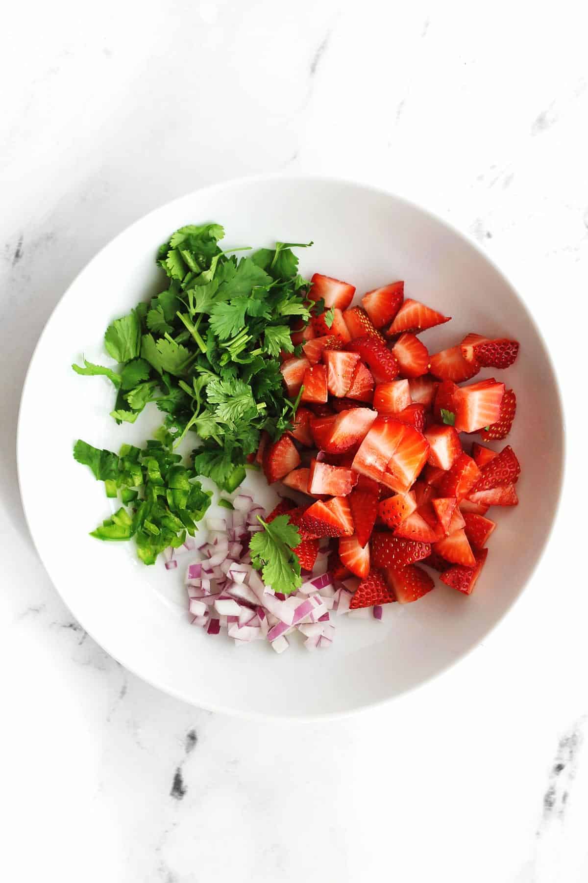 Ingredients for strawberry salsa in a white bowl
