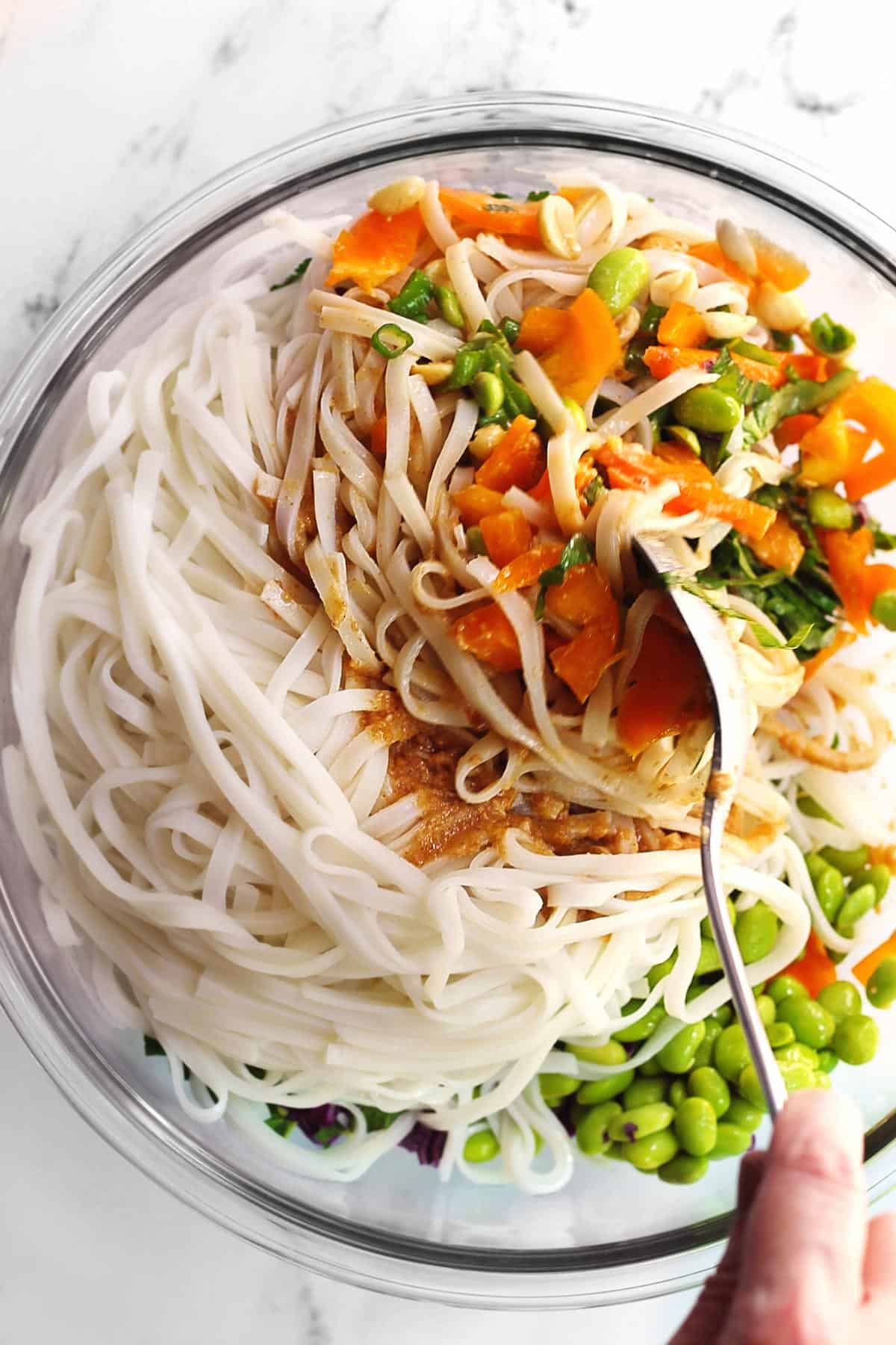 Vegan Thai peanut noodle salad being tossed together