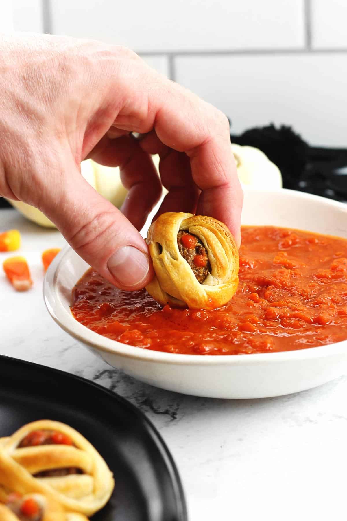 Vegetarian mummy meatball dipped in marinara sauce