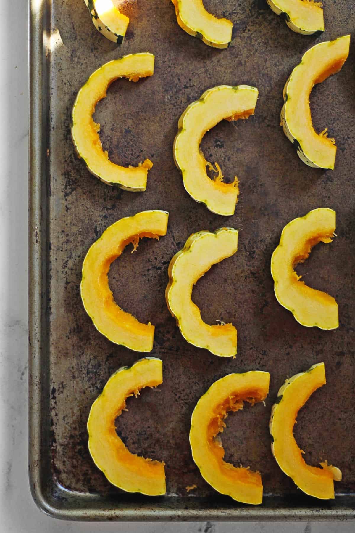 Slices of delicata squash on a sheet pan
