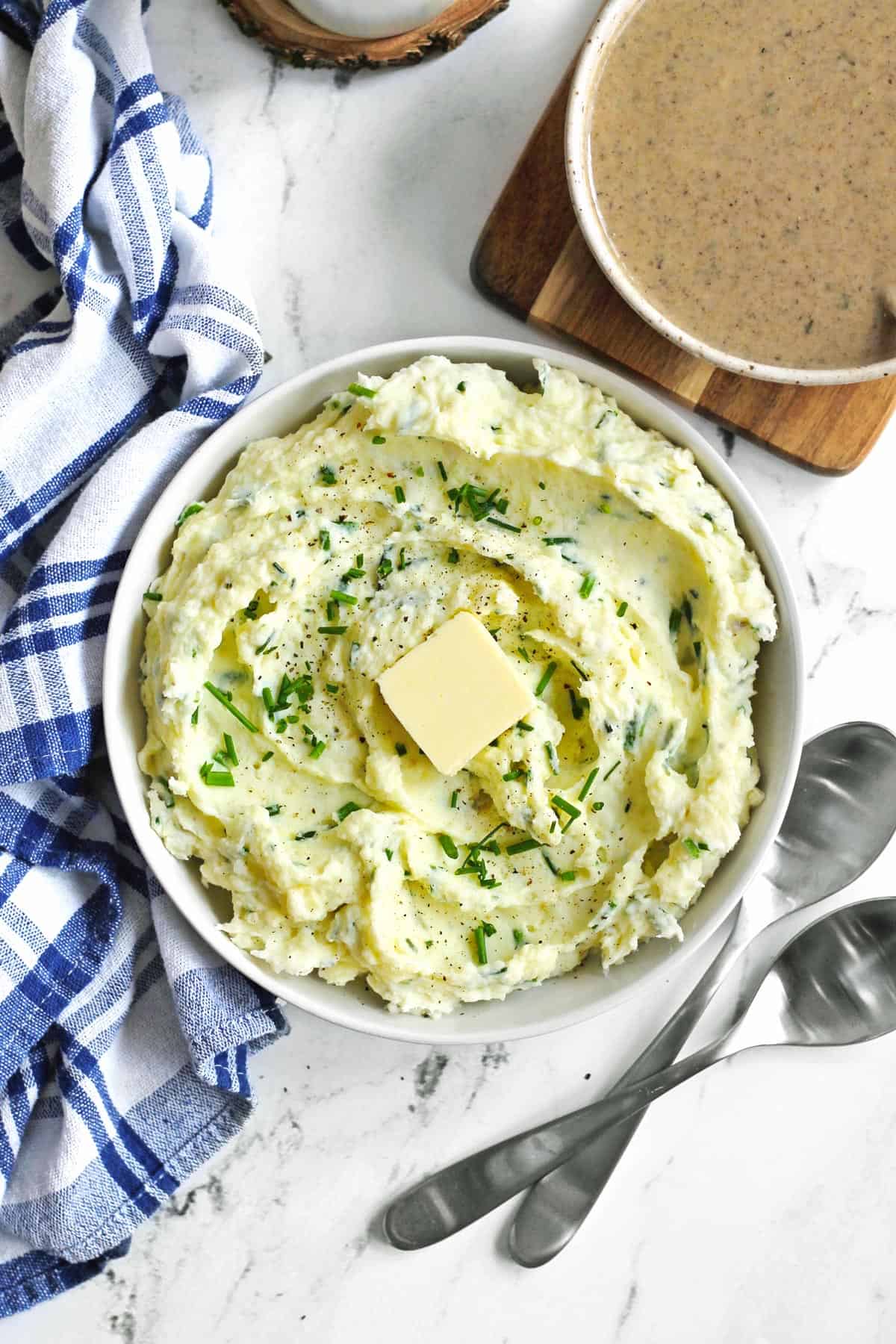 Sour cream and chive mashed potatoes with butter in a white bowl