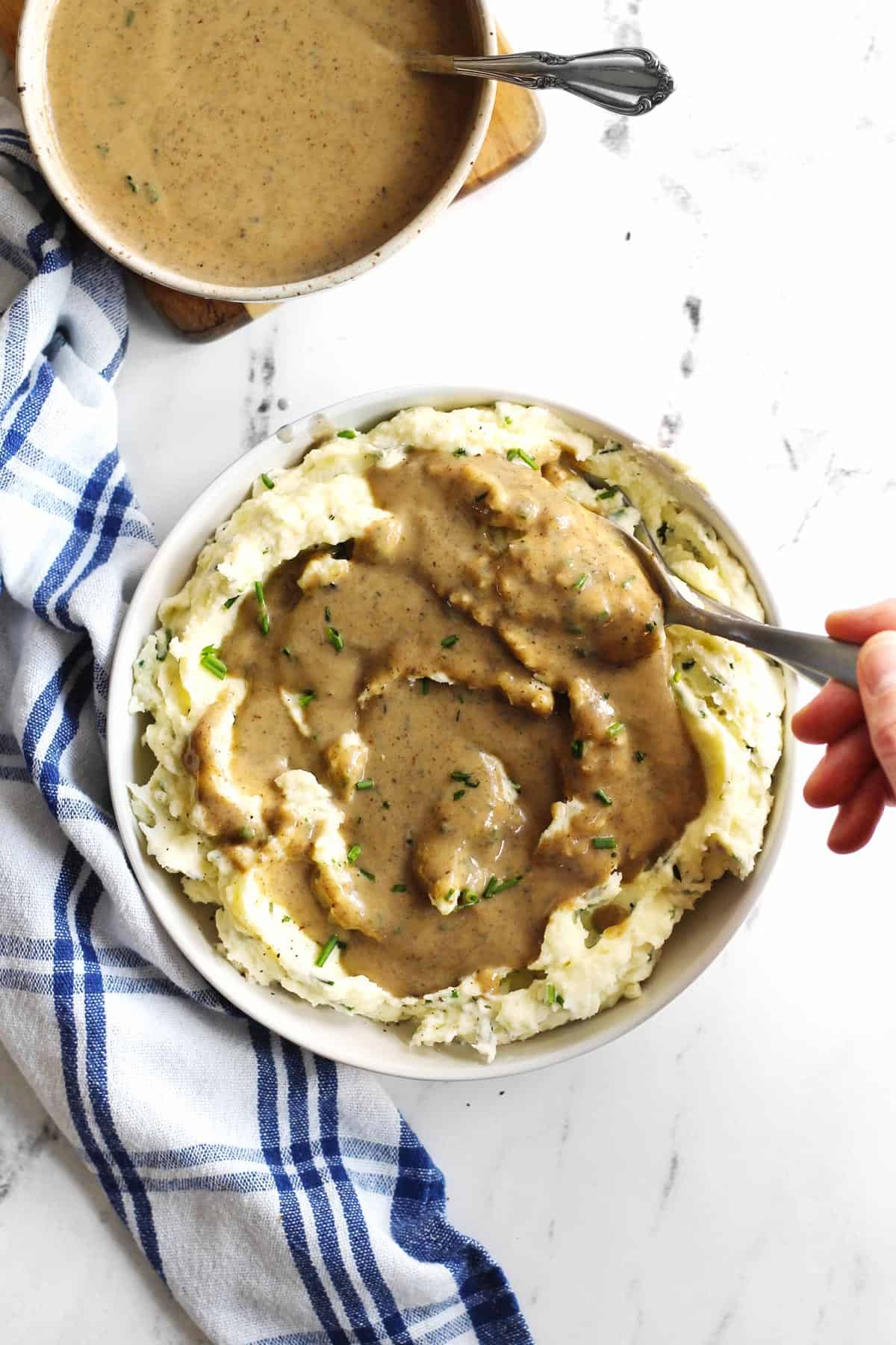 Mashed potatoes topped with gravy in a white bowl