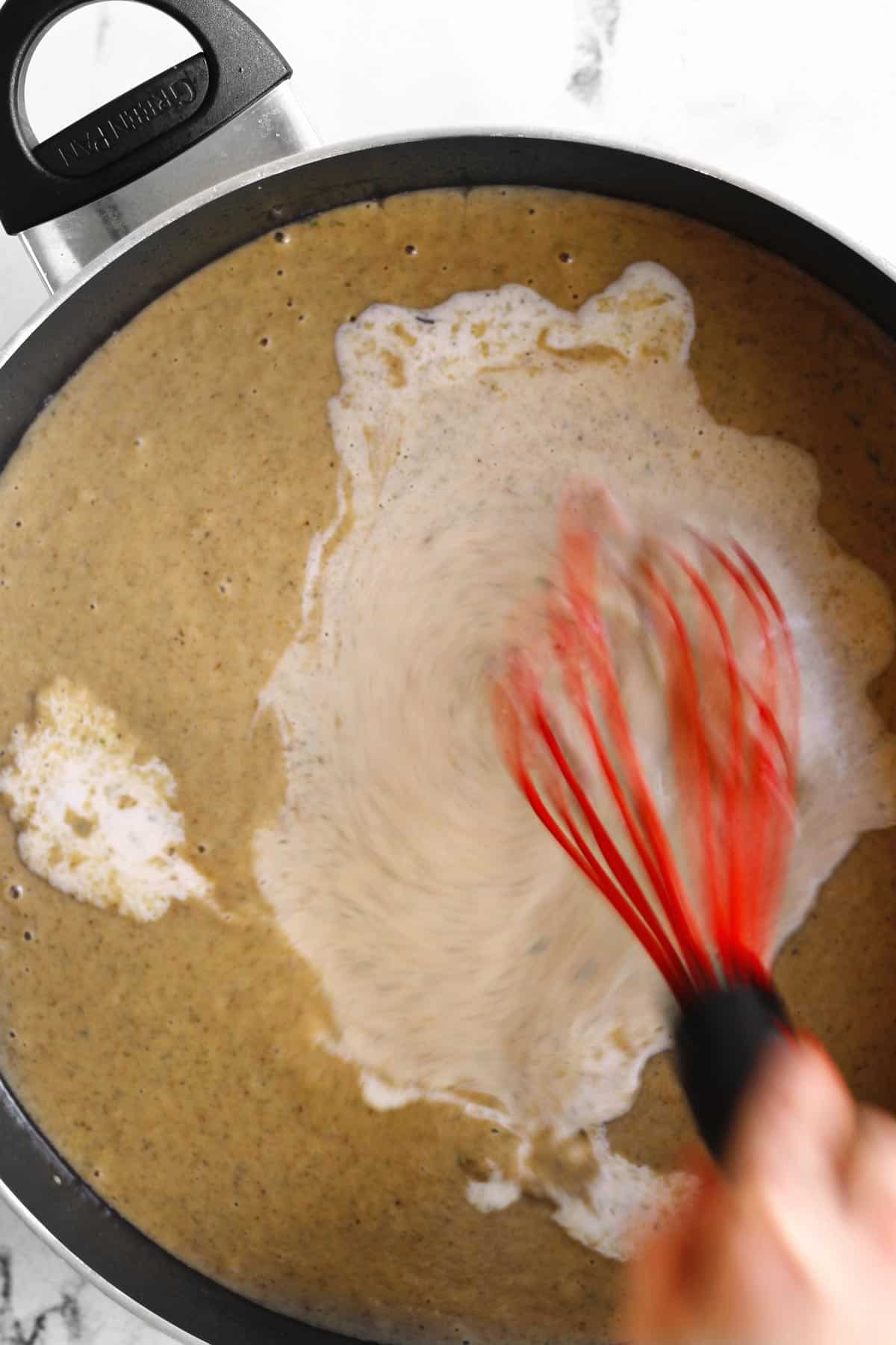 Adding cream to gravy with a whisk