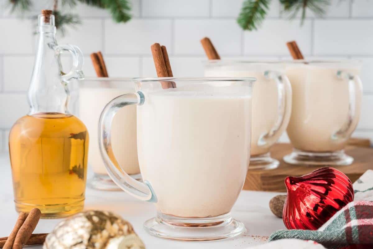 Cups of bourbon eggnog with a bottle of bourbon