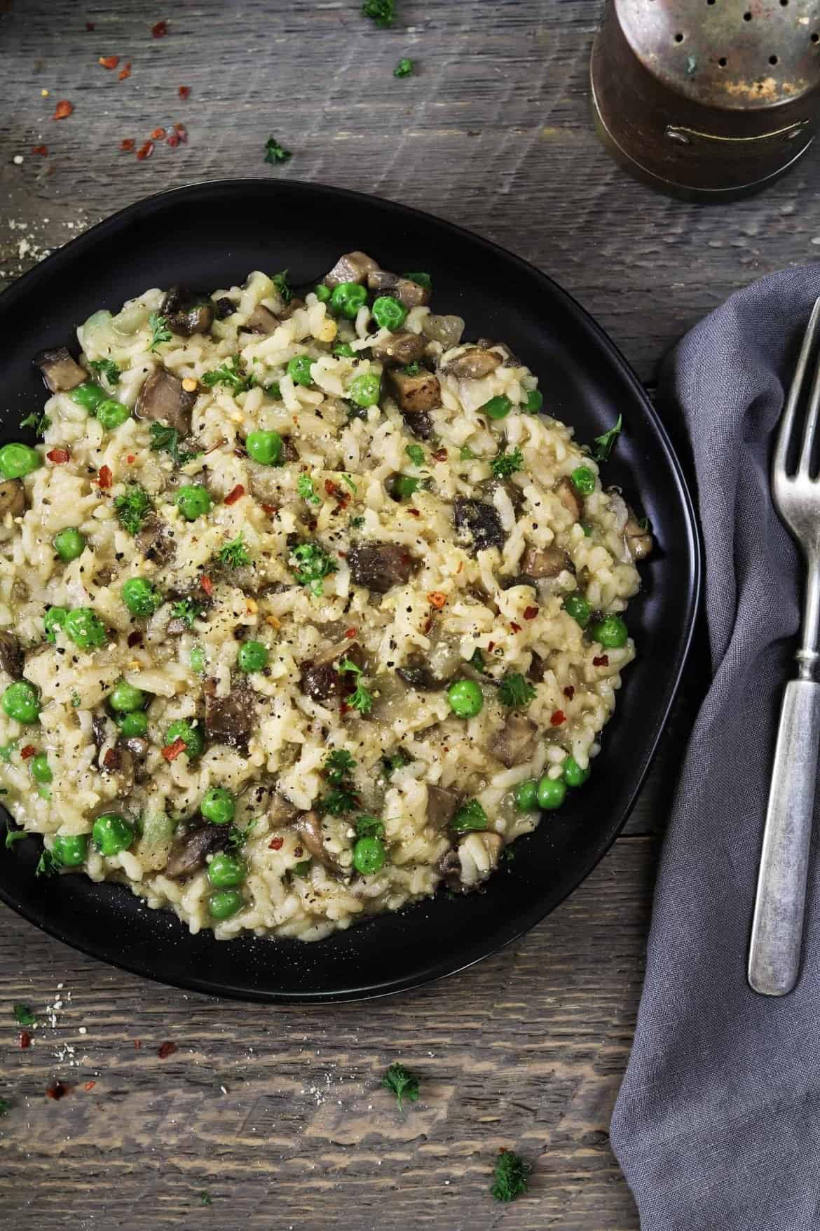 A picture of mushroom risotto with peas on a wooden table
