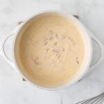 Sour cream enchilada sauce in a white dutch oven.
