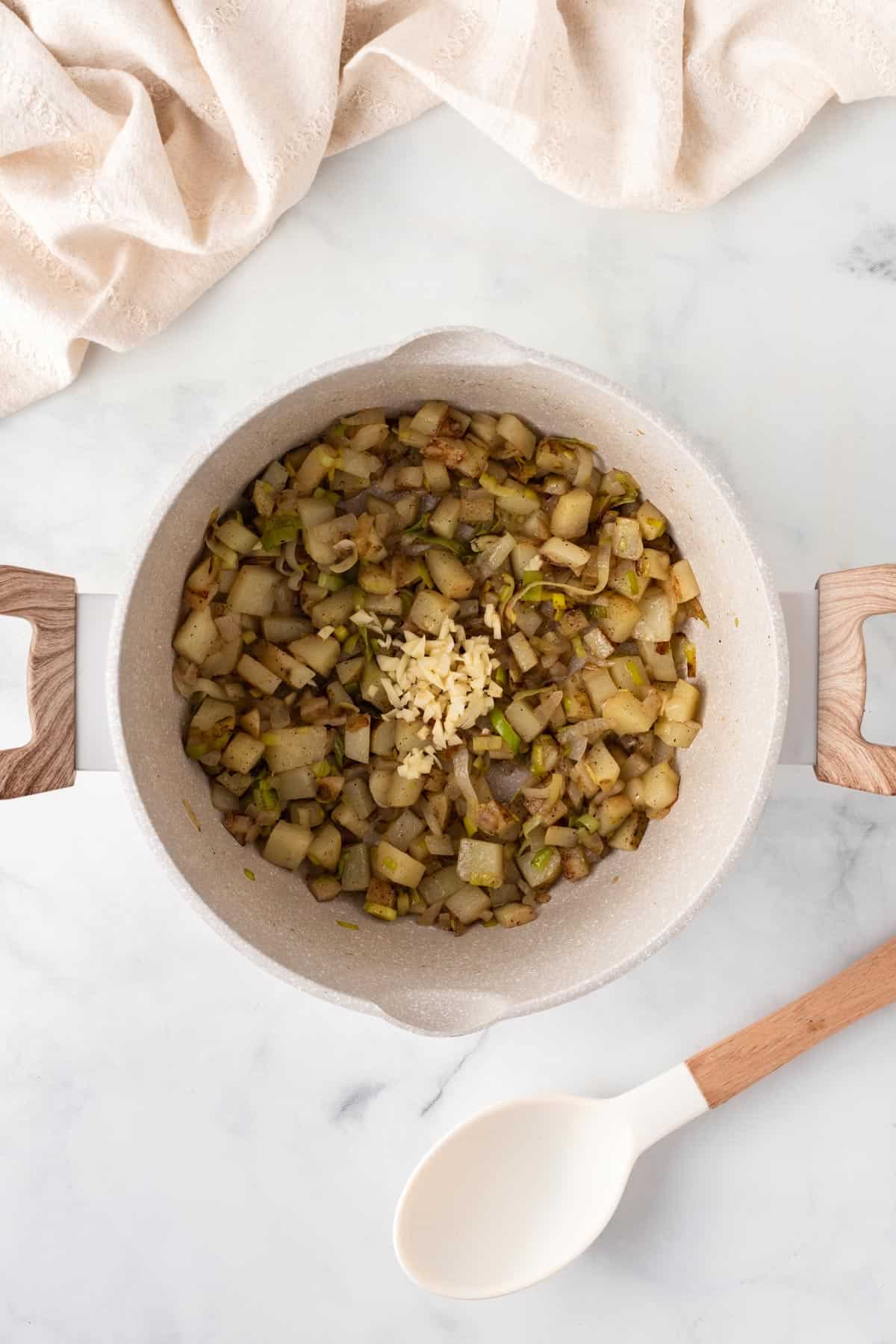 A picture of cooking potatoes and garlic in a soup pot.