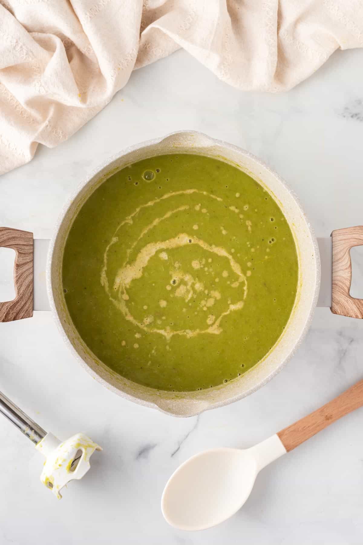 A picture of vegan creamy asparagus soup blended in a soup pot.