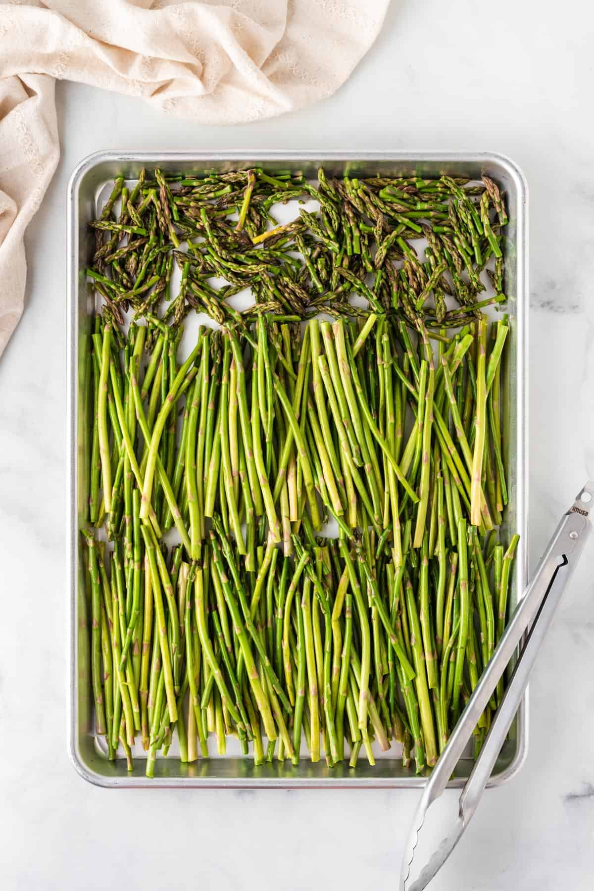 A picture of asparagus stalks on a sheet pan to be roasted.