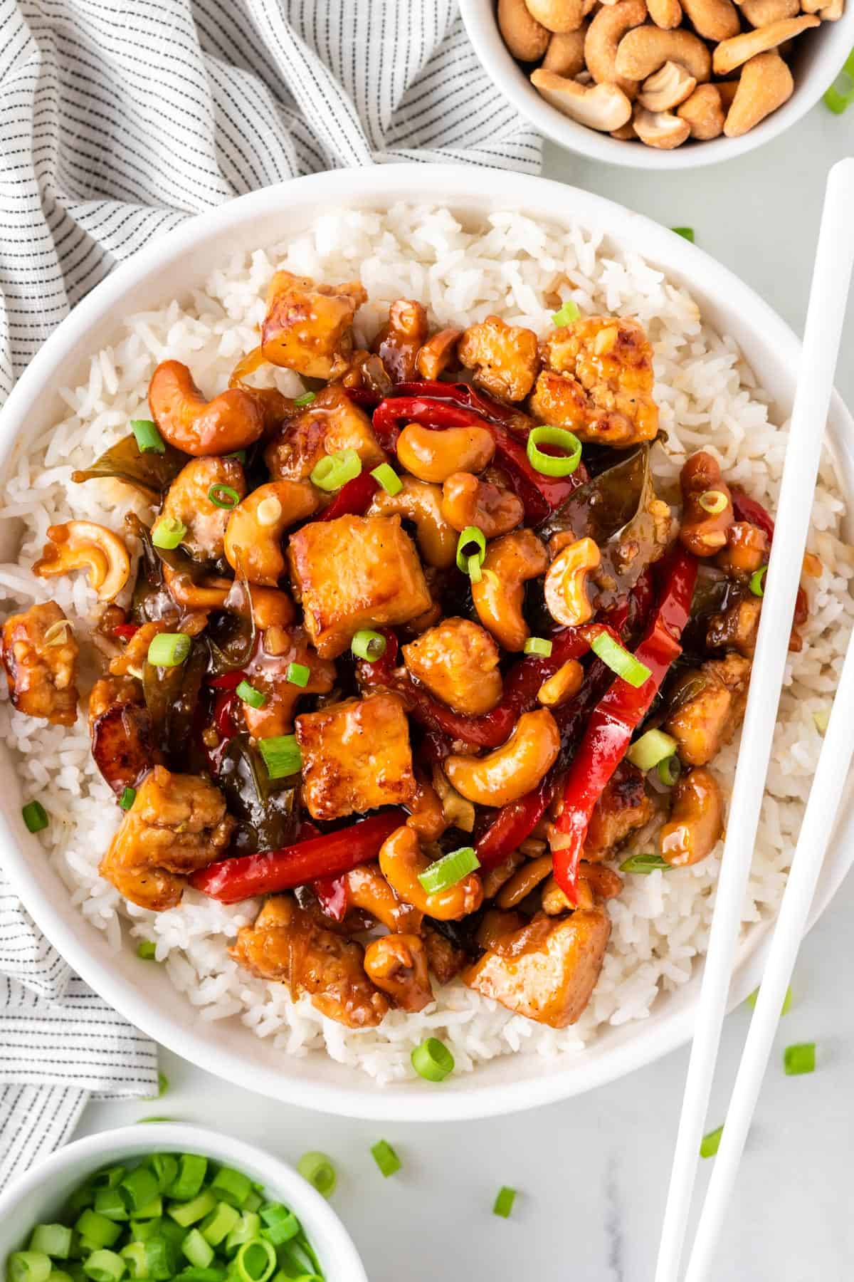 A photo of honey garlic cashew tofu over rice in a white bowl.