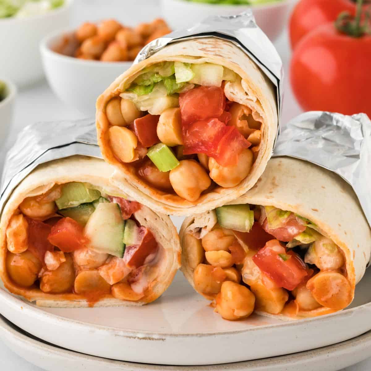 A square photo of three stacked buffalo chickpea wraps in foil.