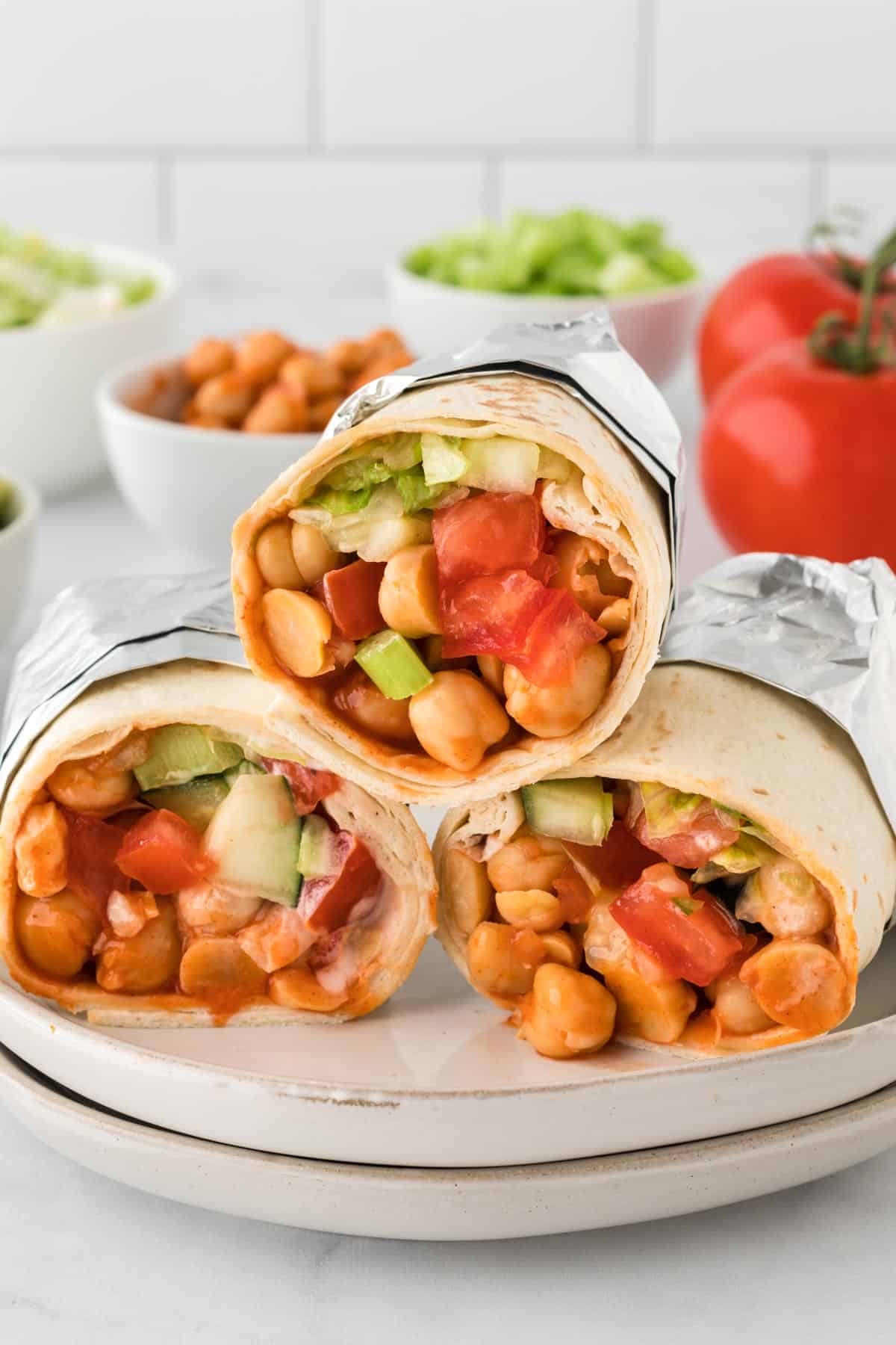 A photo of three buffalo chickpea wraps stacked on two plates.