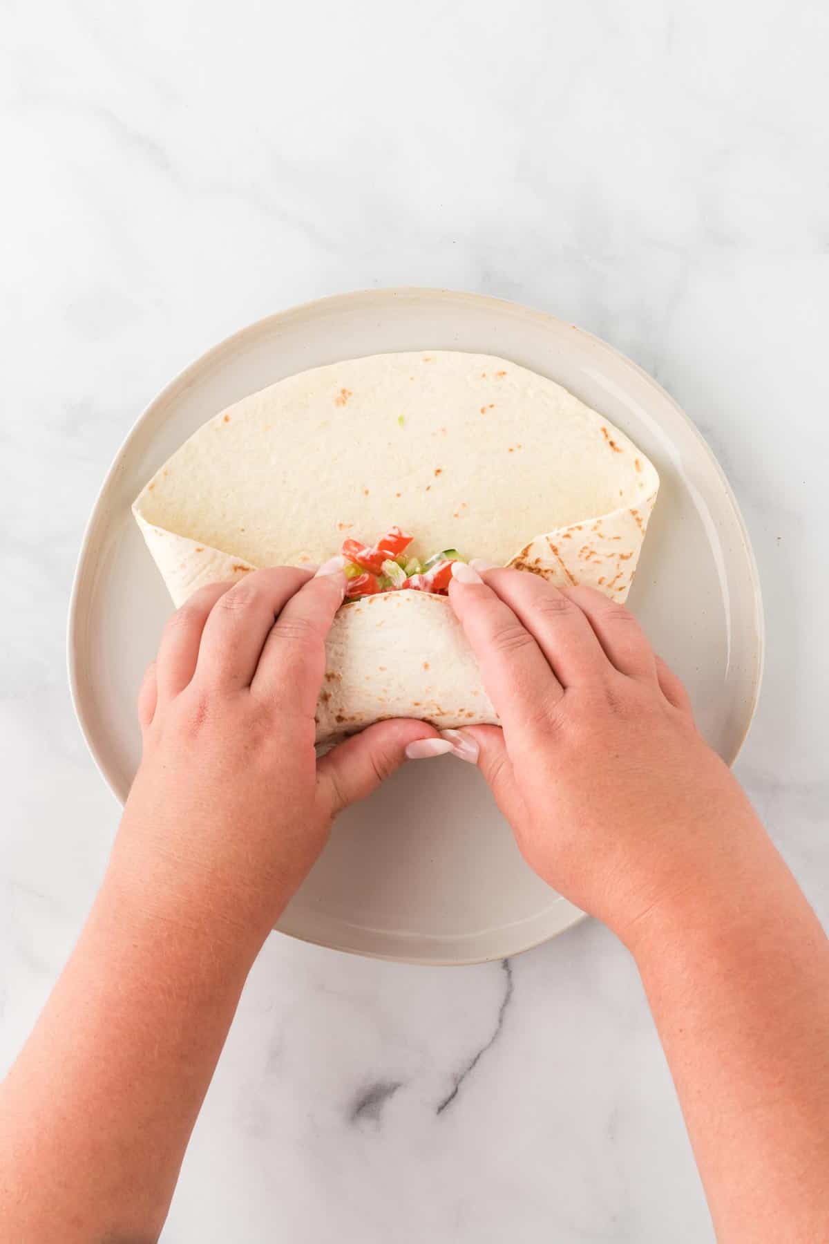 A photo of hands rolling a chickpea wrap.