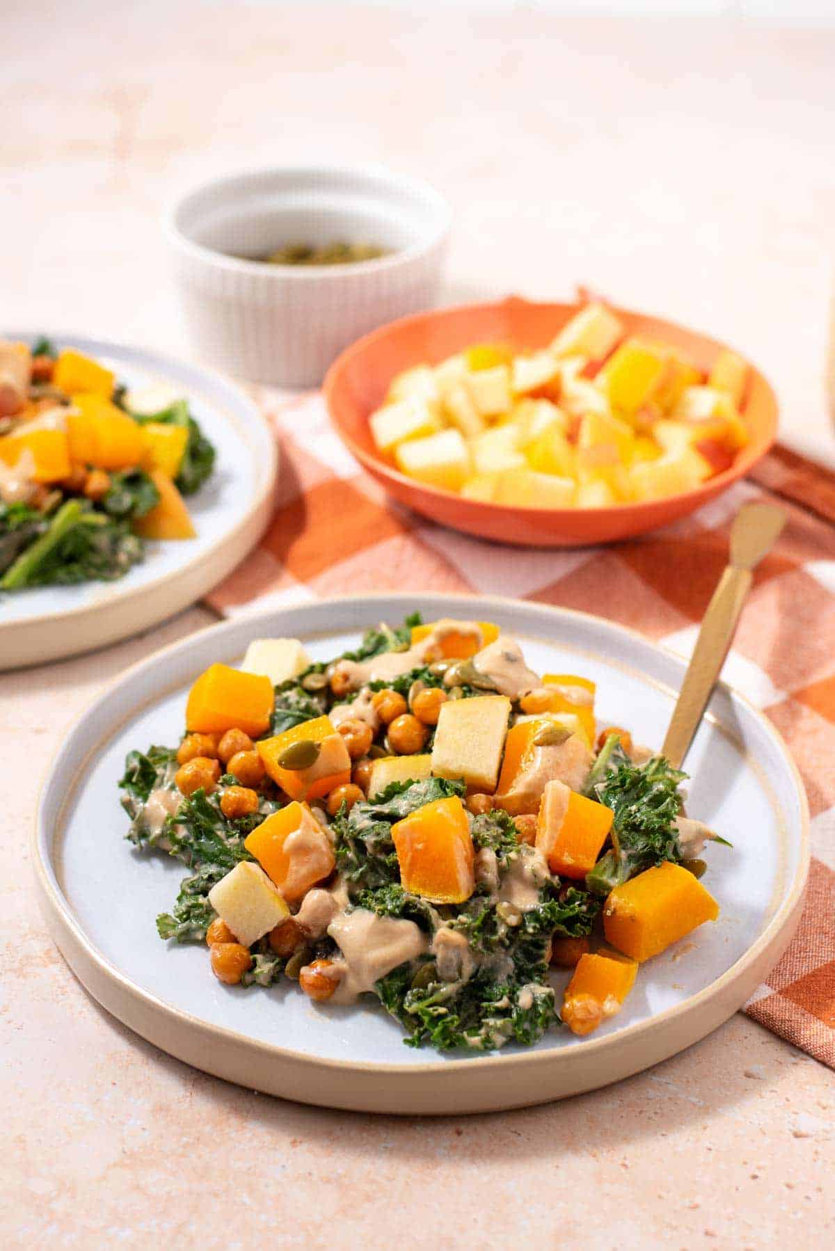 A photo of a butternut squash and kale salad on a white plate.