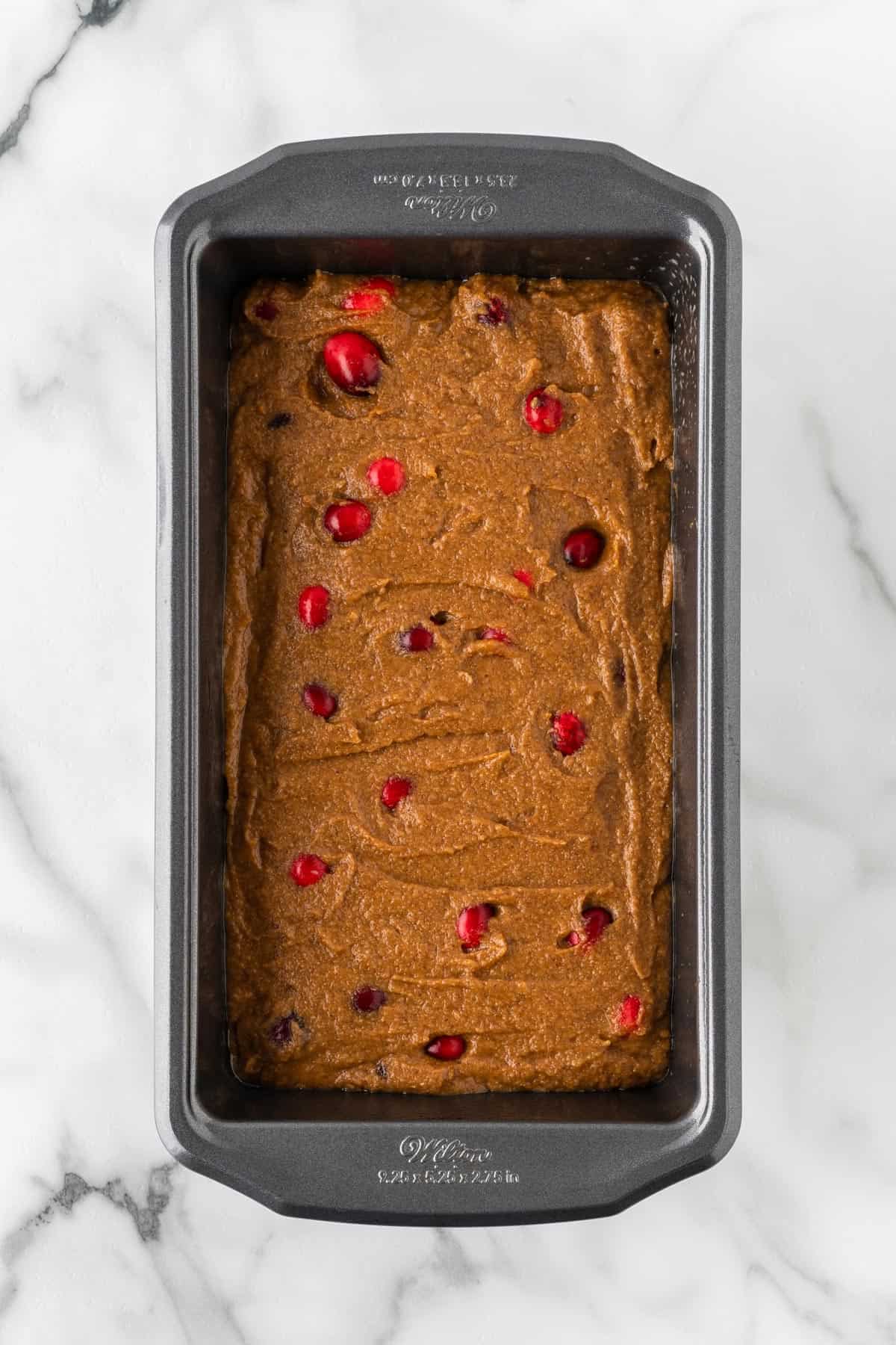 A photo of pumpkin cranberry batter in a loaf pan.