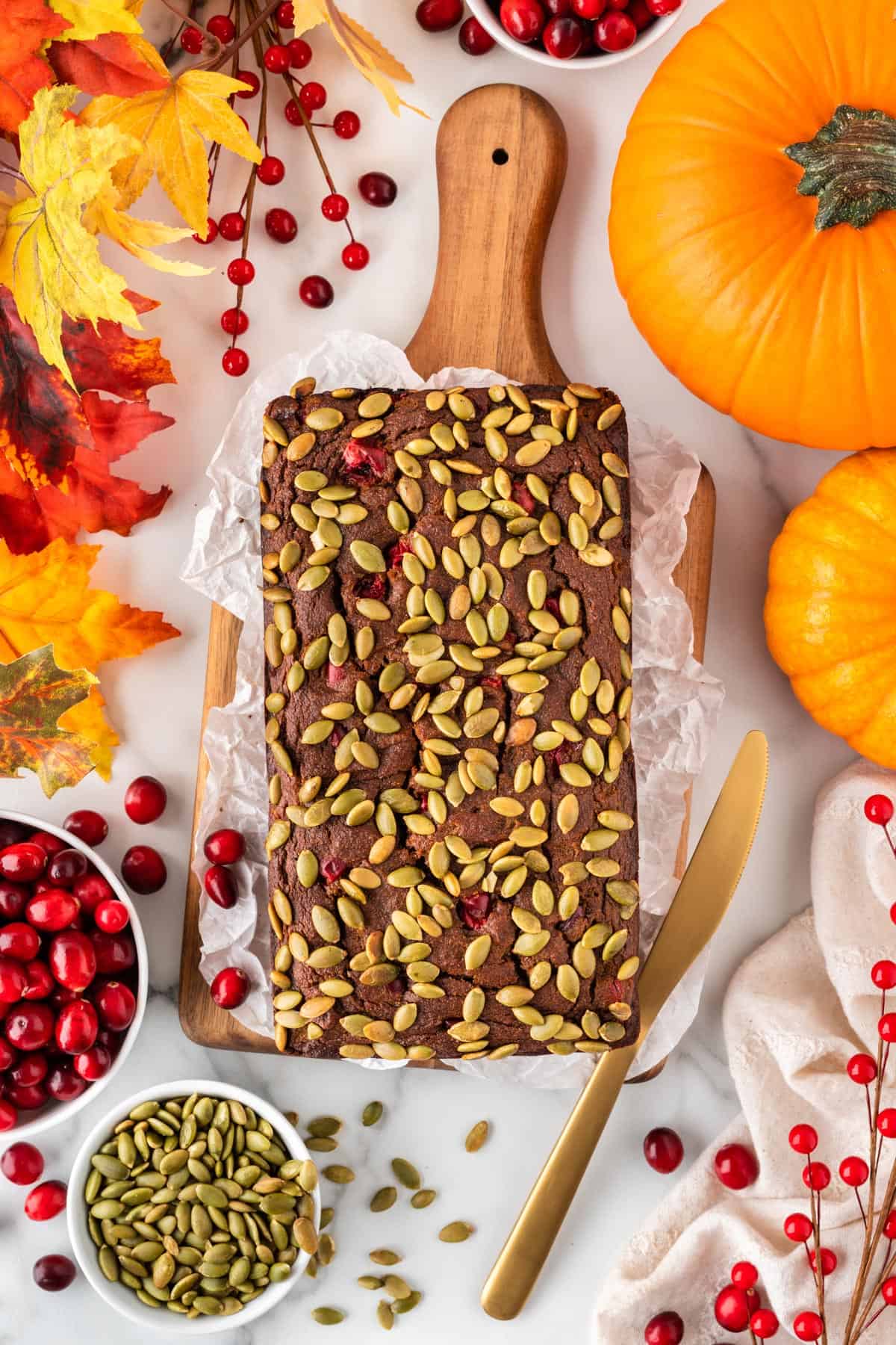 A photo of a pumpkin cranberry loaf surrounded by a fall scene.