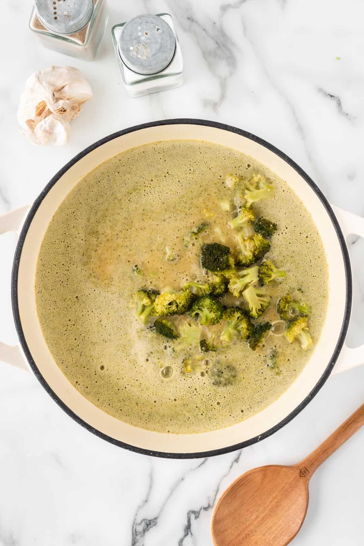 A photo of cooked broccoli in a pot of soup.