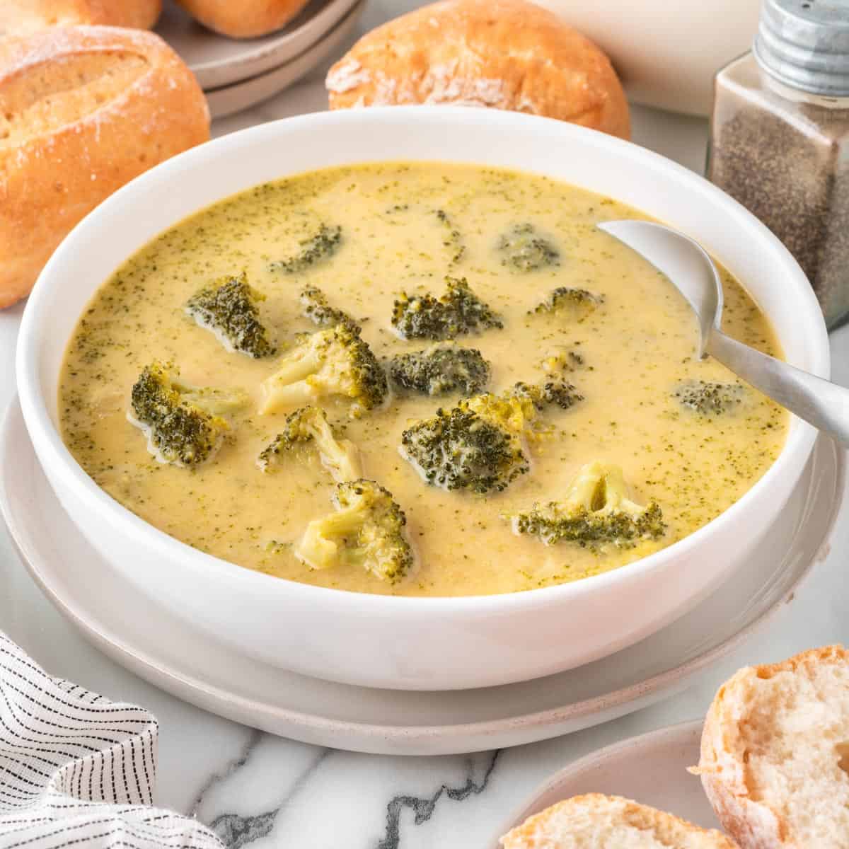 A photo of cheesy broccoli soup in a white bowl with a spoon.