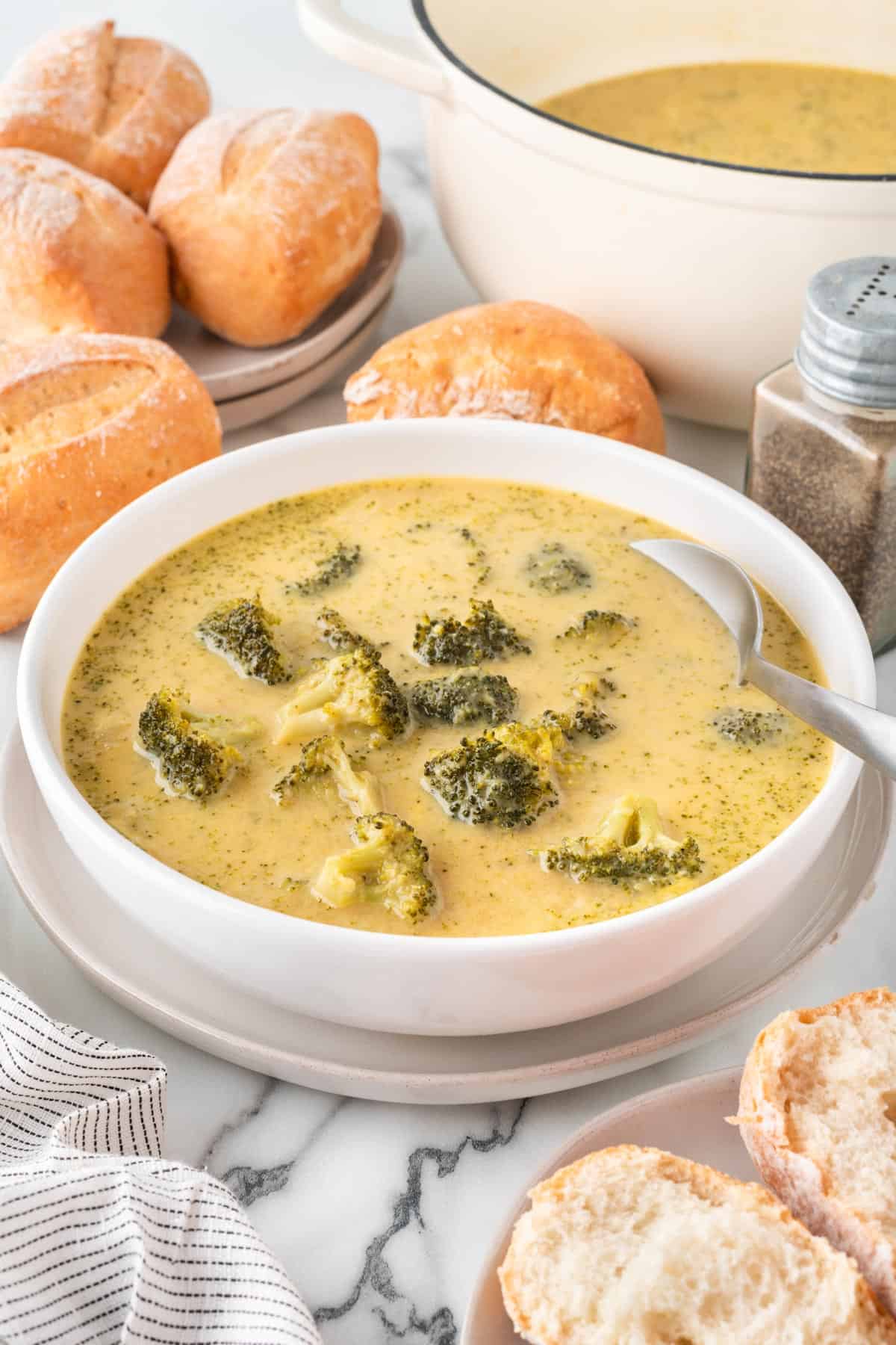 A photo of a bowl of cheesy broccoli soup with a spoon.