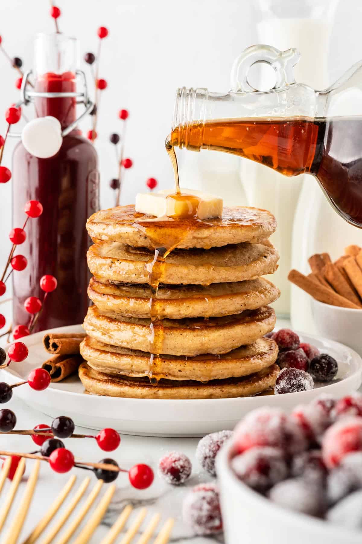 A photo of a stack of pancakes with maple syrup being poured on top.