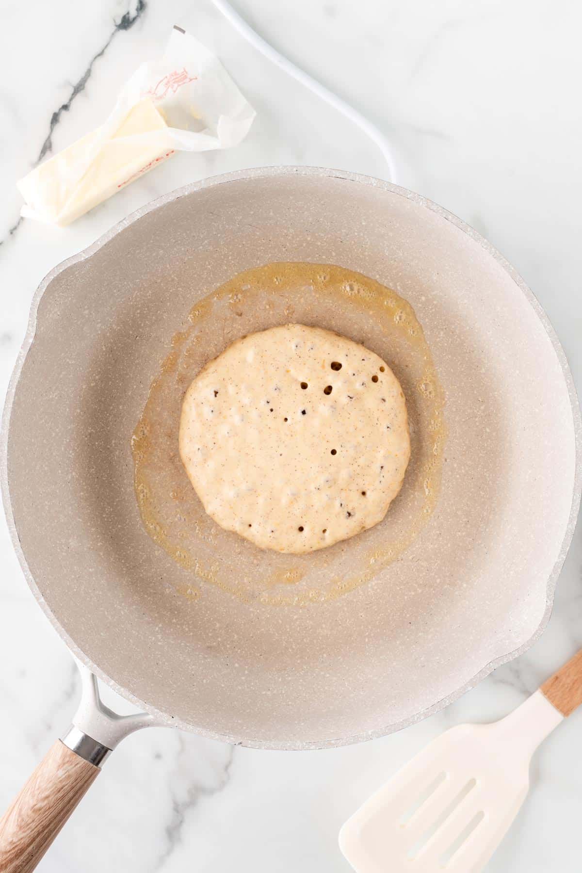 A photo of cooking a single pancake in a skillet.