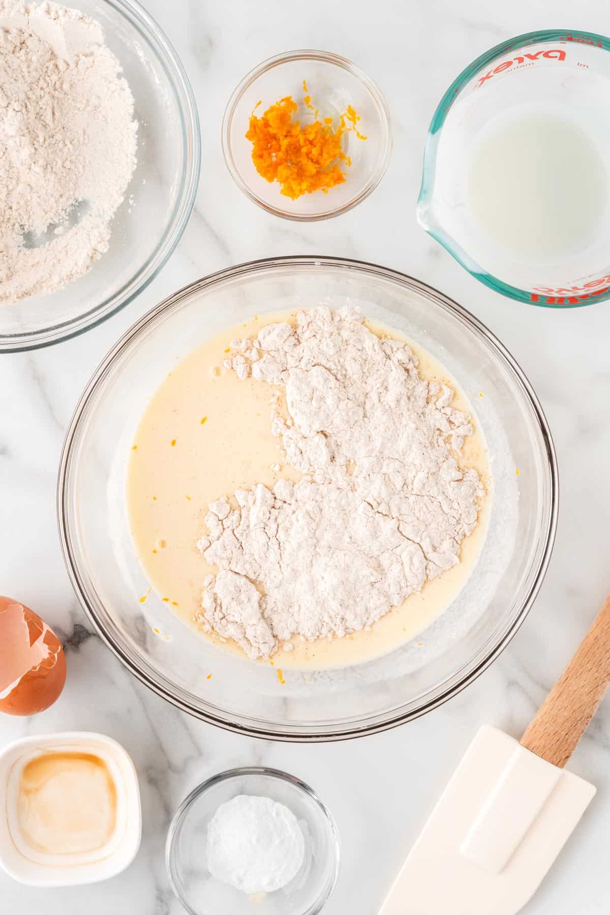A photo of adding dry pancakes ingredients to wet ingredients in a glass bowl.