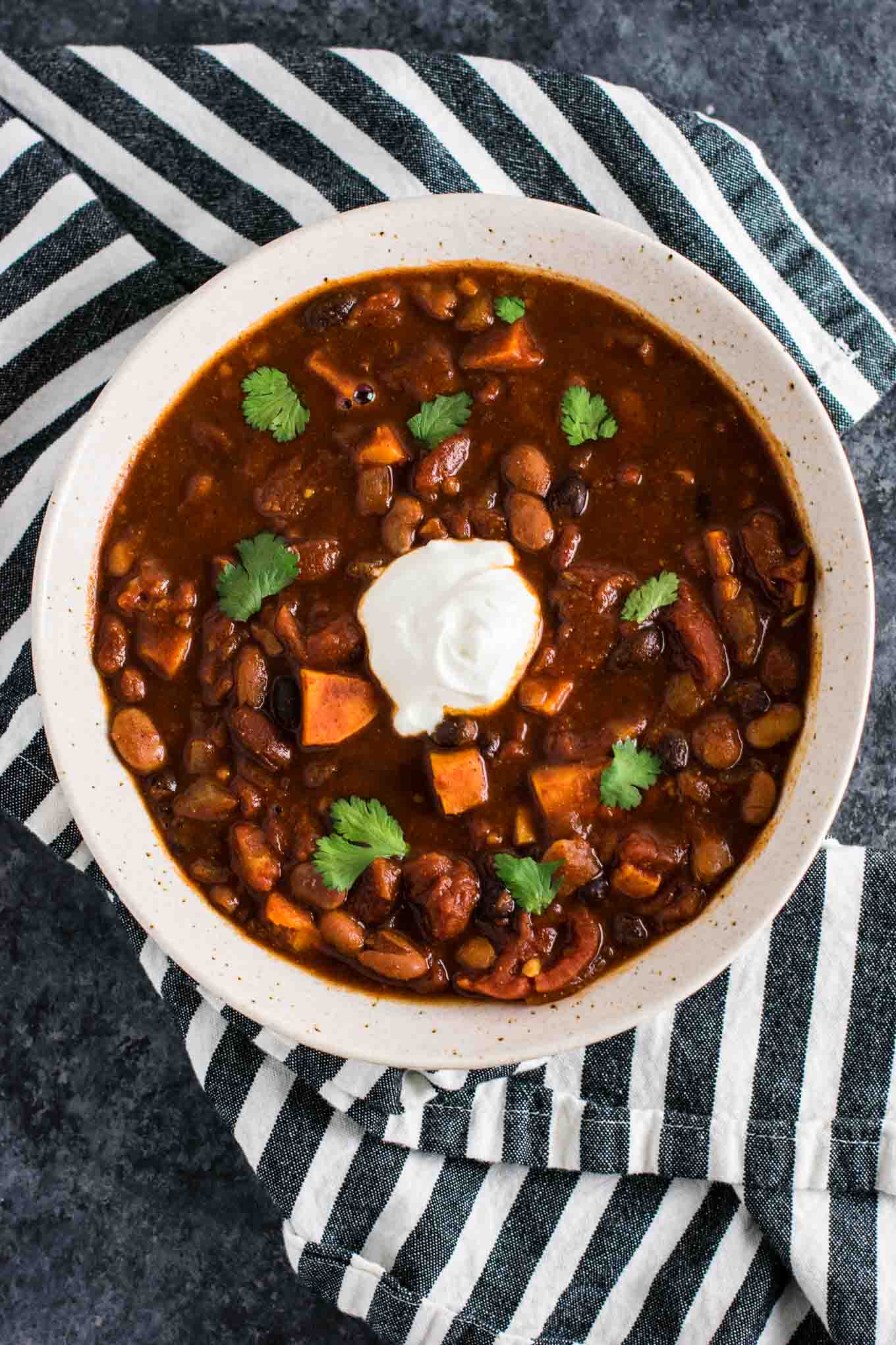 A photo of a bowl of sweet potato chili with a dollop of sour cream on top.