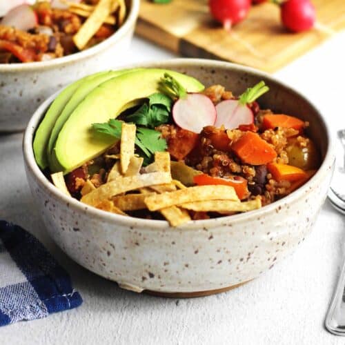 A square photo of a bowl of chili with tortilla strips, radish, and avocado slices.
