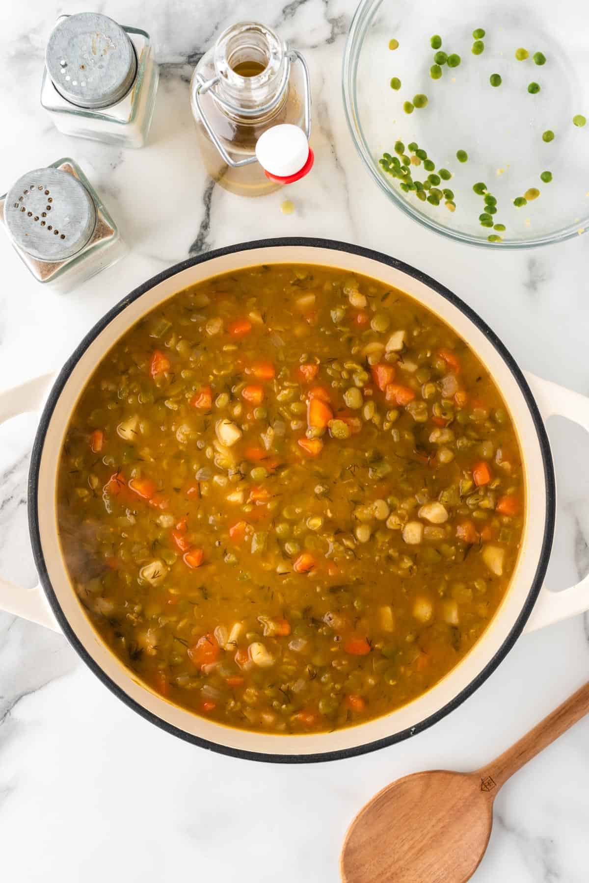 A photo of cooked split pea soup in a white dutch oven.