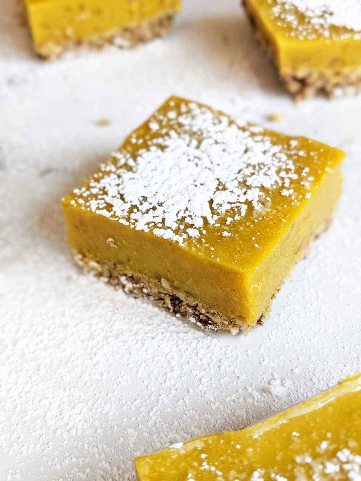 A photo of a vegan lemon bar with powdered sugar on top.