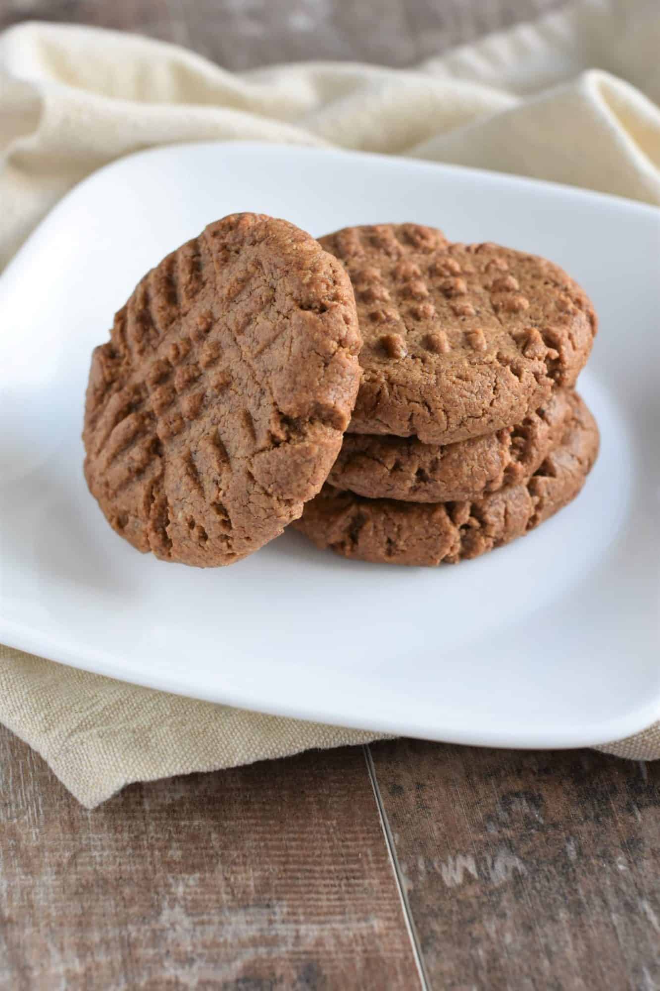 A photo of almond butter cookies stacked on a white plate.
