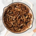 A square photo of burnt onions in a white skillet.